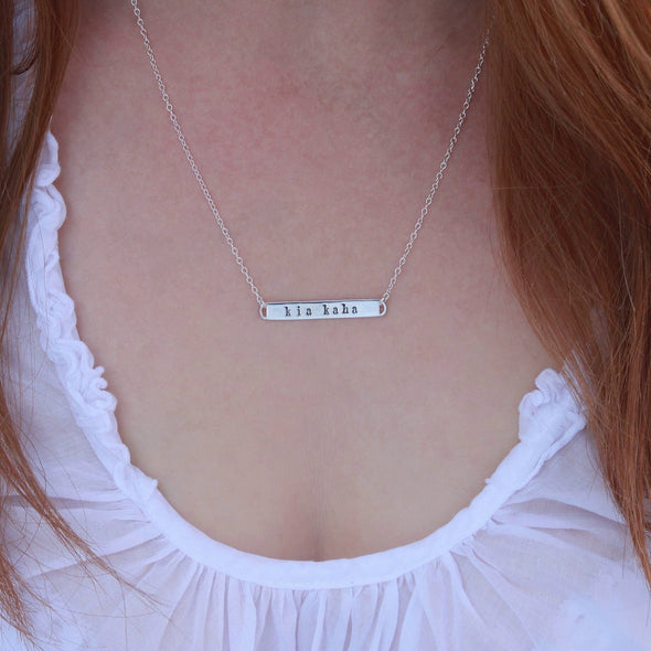 Sterling Silver hand-stamped 'kia kaha' necklace on neck.