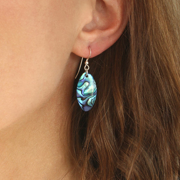 Paua shell oval earrings on model ear