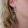 Sterling Silver arch triangle earrings with clear quartz bead on models ear