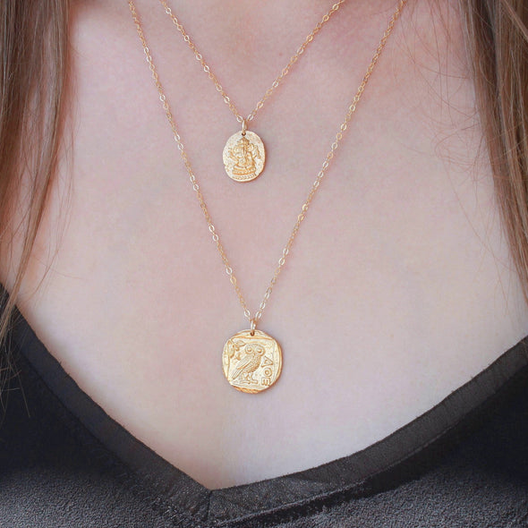 Gold ganesh & owl pendants layered on womans neck.