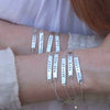 9x Sterling Silver hand-stamped word bracelets on wrists.