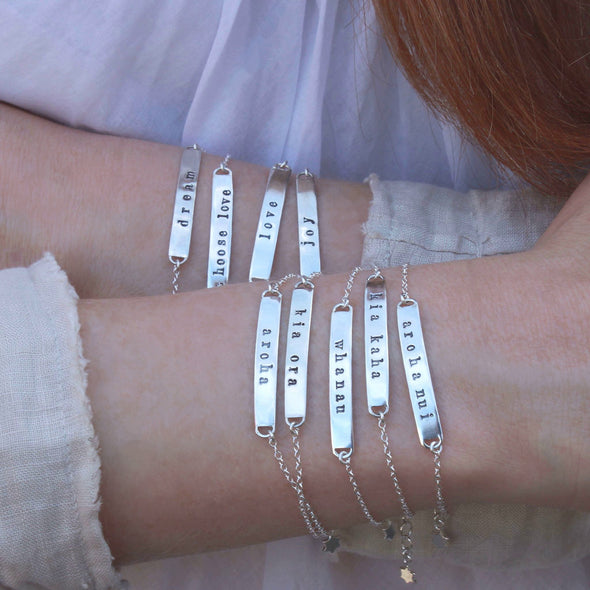Sterling silver message bracelets on wrists - assorted words