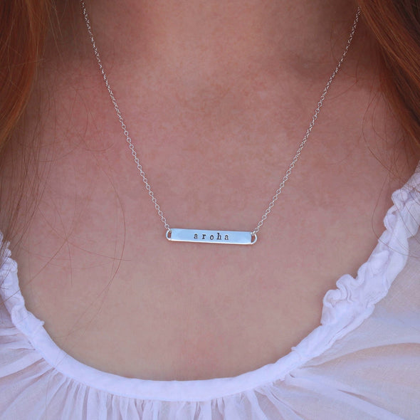 Sterling Silver hand-stamped 'aroha' necklace on neck.