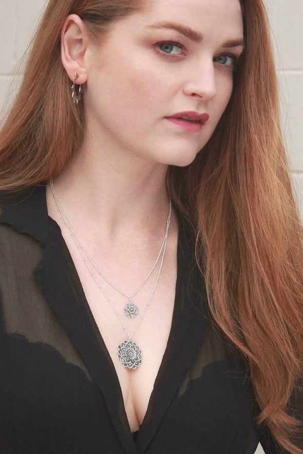 Model wearing layered Mandala necklaces and hoop earrings