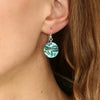 Paua Round earrings on ear.