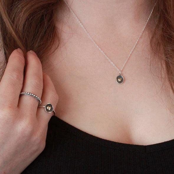 2 Sterling silver rings on models hand and bronze heart necklace