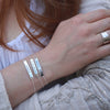 Three sterling silver message bracelets on wrist