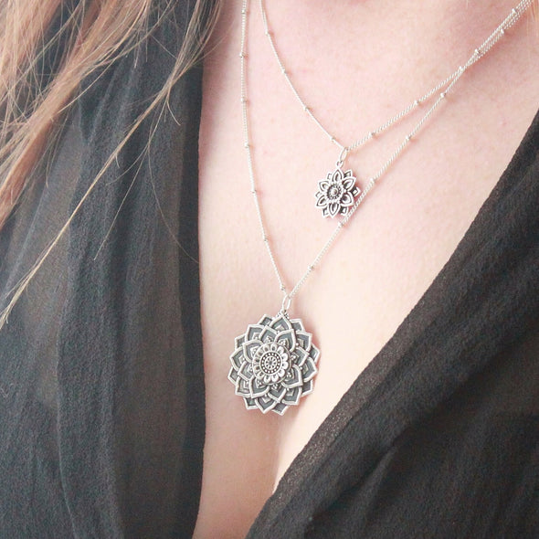Sterling silver mandala layered necklaces on neck.