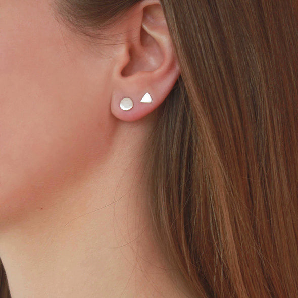Sterling Silver petite triangle and round studs on models earlobe