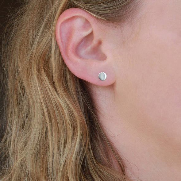 Sterling Silver petite round stud earrings on models earlobe
