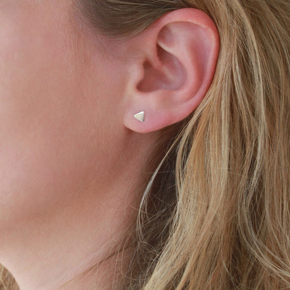 Sterling Silver petite triangle studs on models earlobe
